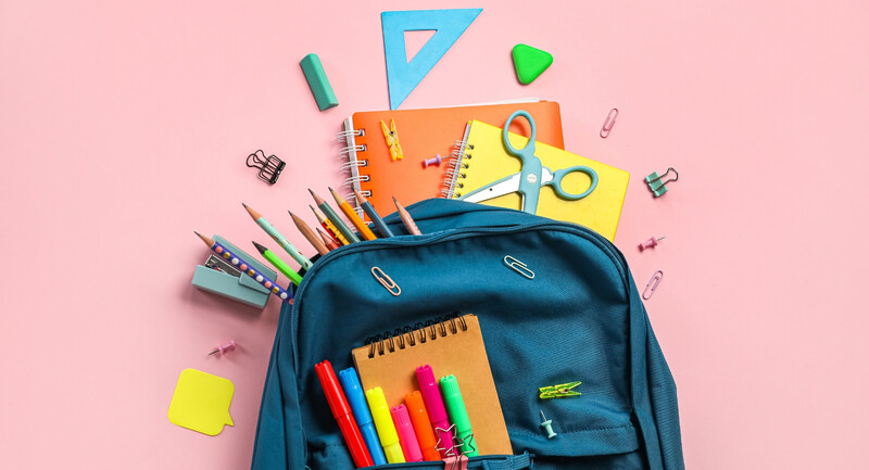 School backpack with school supplies on pink background.